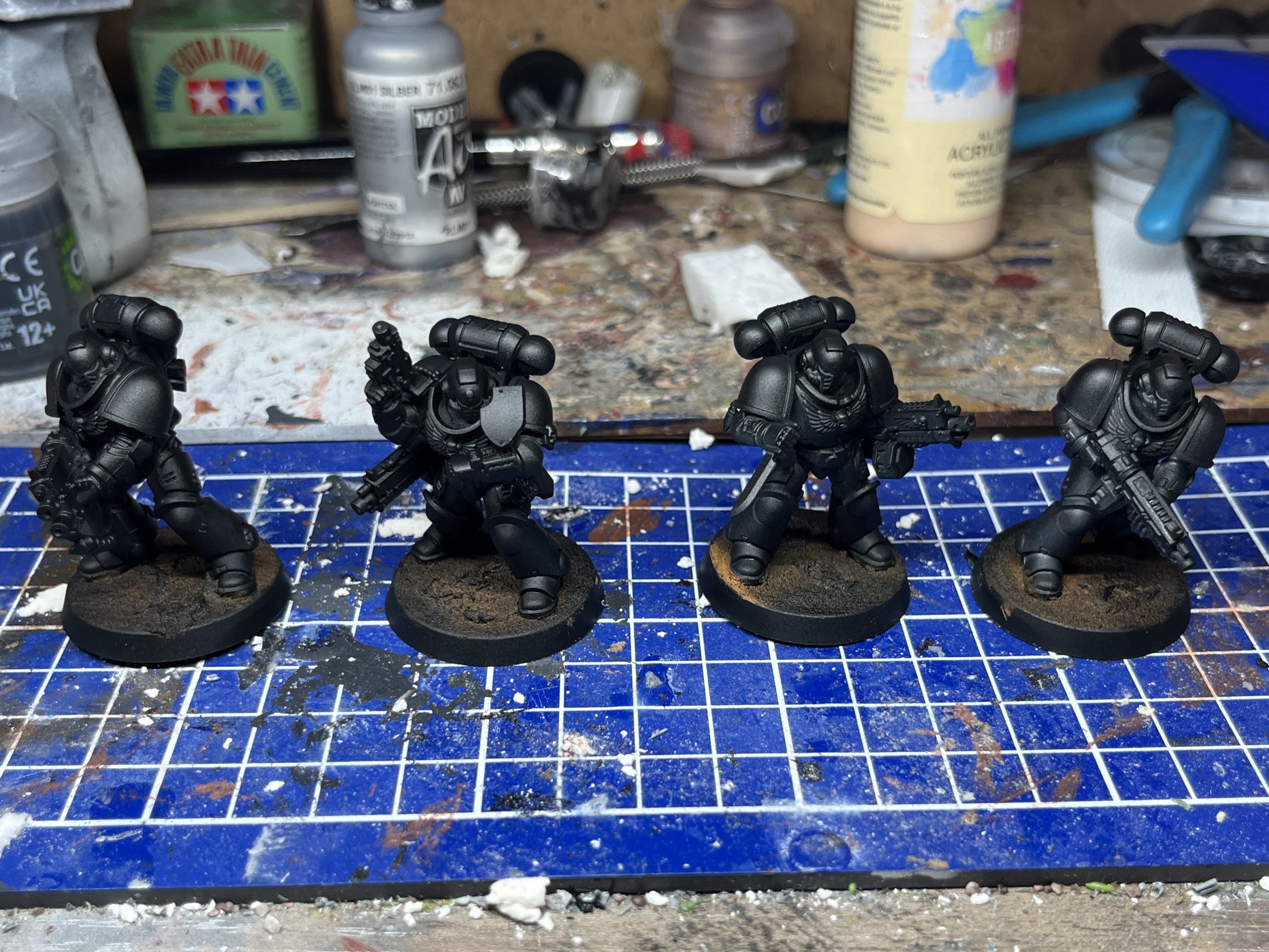 Photograph of a set of 5 28mm space marine. One of the models is painted and the other 4 are grey plastic.